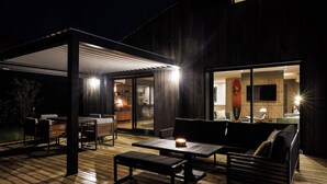 Un patio al aire libre con mobiliario de madera y una mesa con una vela.