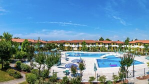 A hotel with multiple swimming pools, a landscaped garden, and a row of yellow buildings with red roofs. - Relaxing getaway with pool and garden in Bibione (San Michele Al Tagliamento)
