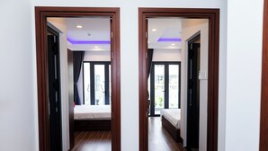 A modern hotel room with a wooden floor, a bed, a window with curtains, and a view of the outside. - Suka Hotel (Tan Ninh)