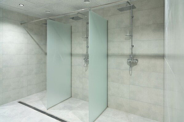A modern bathroom with two glass-enclosed shower stalls, a tiled floor, and a ceiling with recessed lighting. - Ani Forest Hills Hotel and Resort (Dilijan)