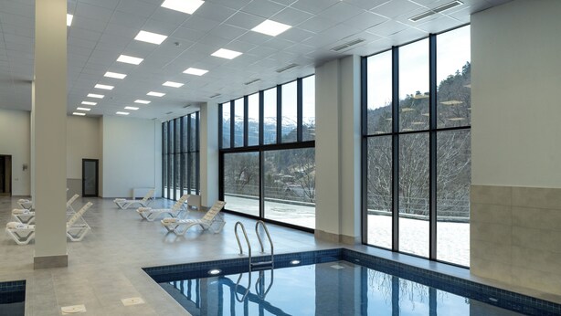 Una amplia piscina interior con vistas despejadas a un paisaje nevado a través de grandes ventanales.