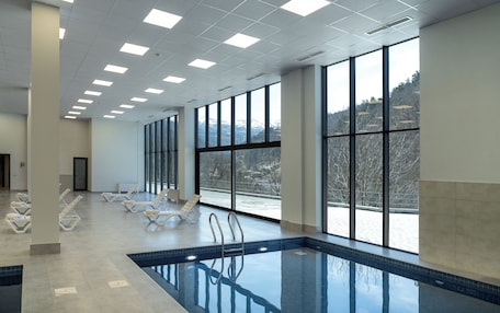 A large indoor swimming pool with clear views of a snowy landscape through large windows.