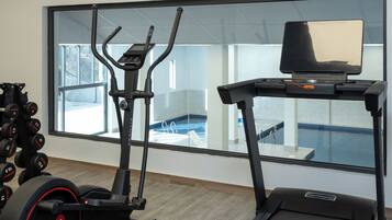 A gym with treadmills, a rowing machine, and dumbbells.