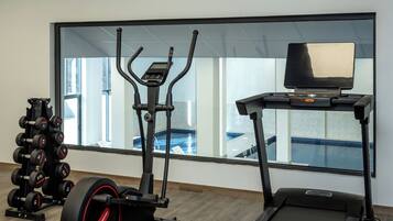 A gym with a treadmill, elliptical, and weight rack.