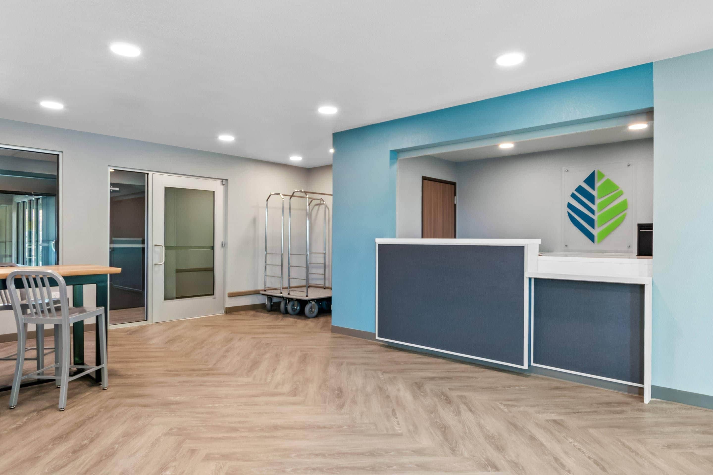A reception area with a desk, chairs, a coat rack, and a wall-mounted logo.