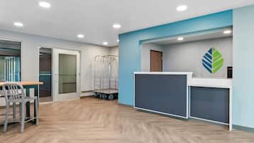 A reception area with a desk, chairs, a coat rack, and a wall-mounted logo.