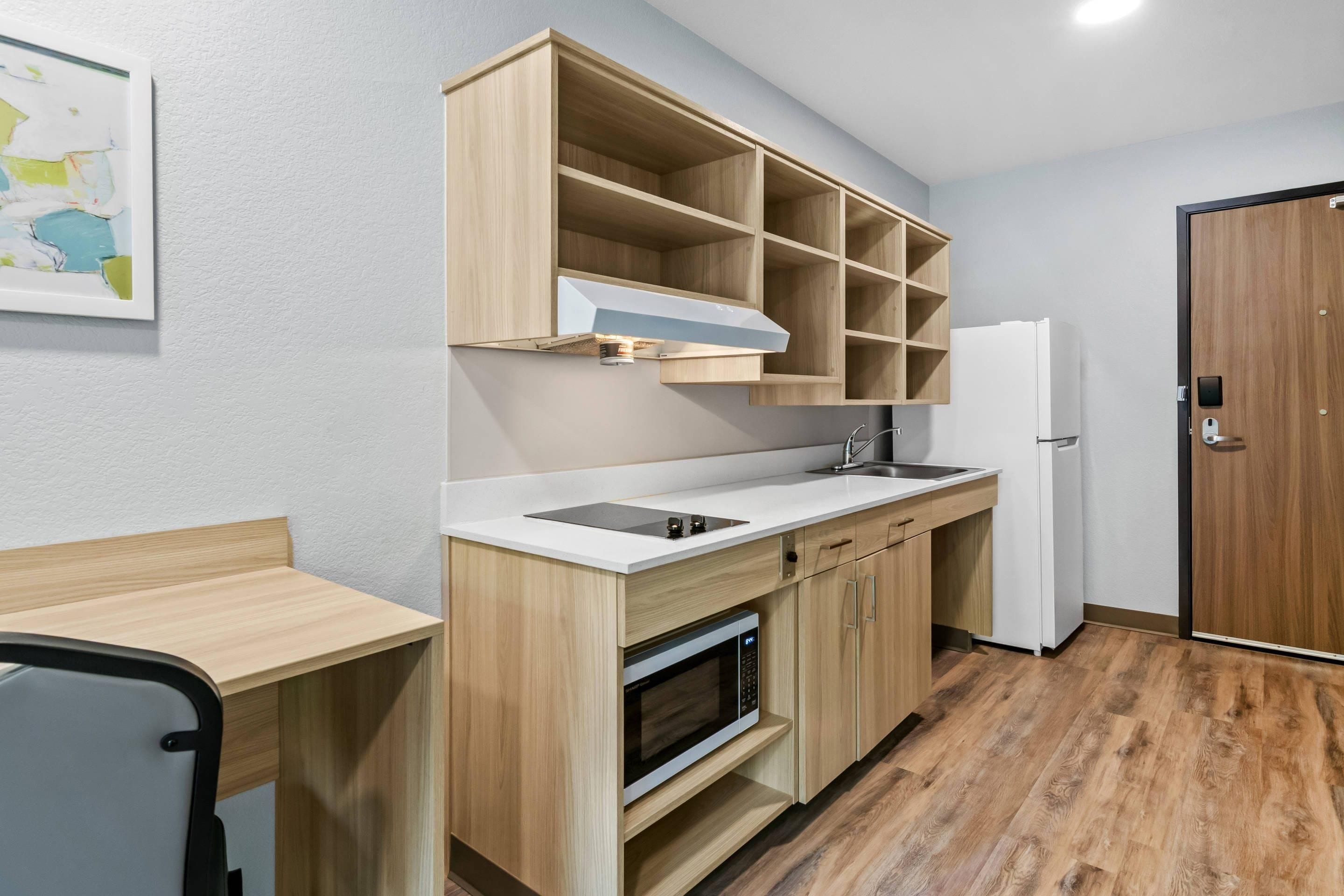 Una cocina compacta con microondas, estufa y armarios de madera.
