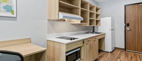Una cucina compatta con forno a microonde, piano cottura e mobili in legno.