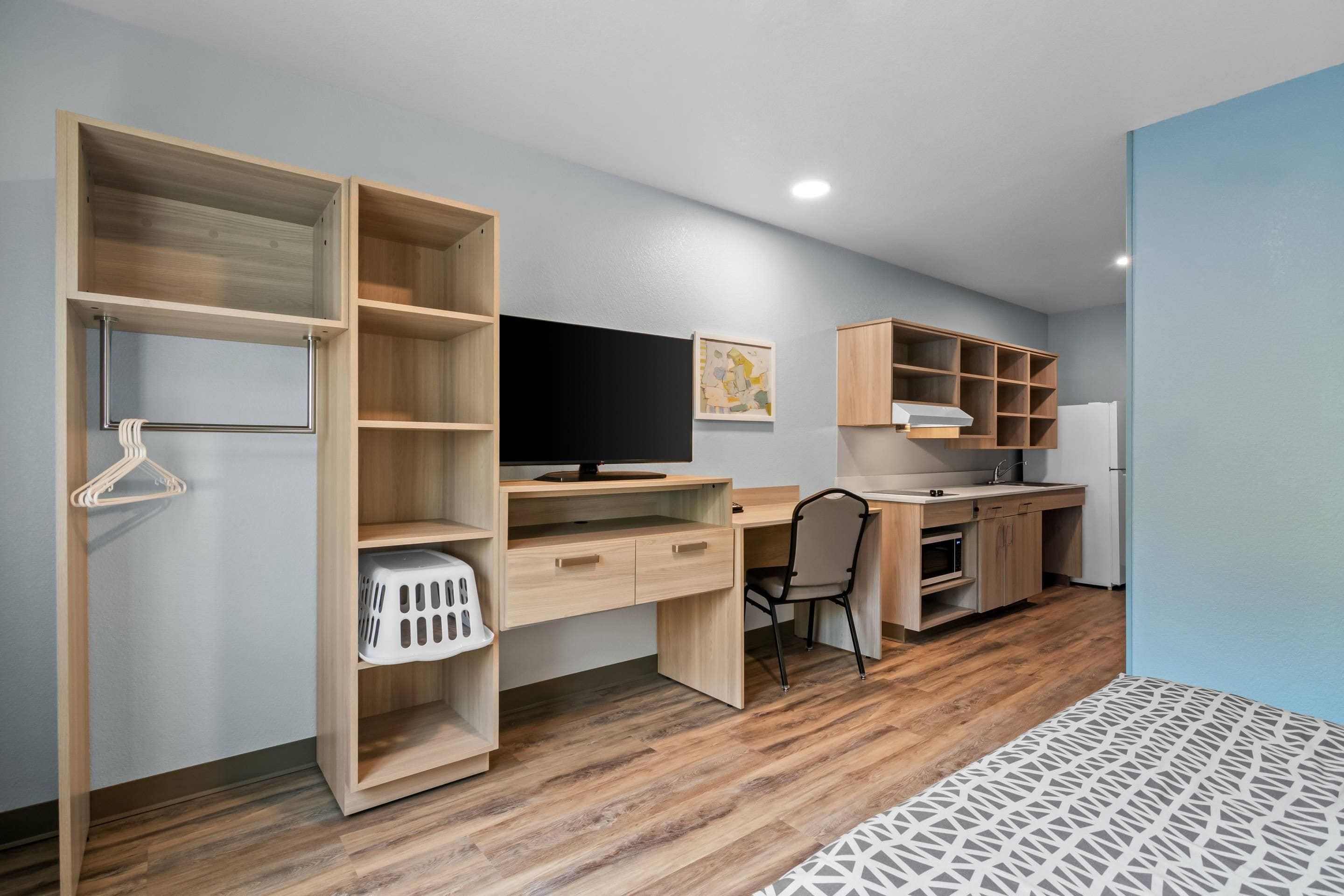 A modern room with a wooden desk, a chair, a television, and built-in shelving.