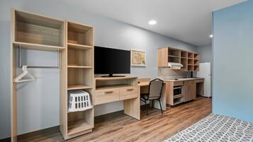 A modern room with a wooden desk, a chair, a television, and built-in shelving.