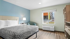 Une chambre d’hôtel comprenant un lit, une chaise, une fenêtre donnant sur la rue et une armoire intégrée.