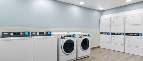 A laundry room with four washing machines and a set of six dryers.