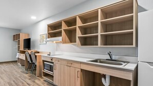 Una cocina moderna con armarios de madera, horno empotrado, un lavamanos y un televisor.