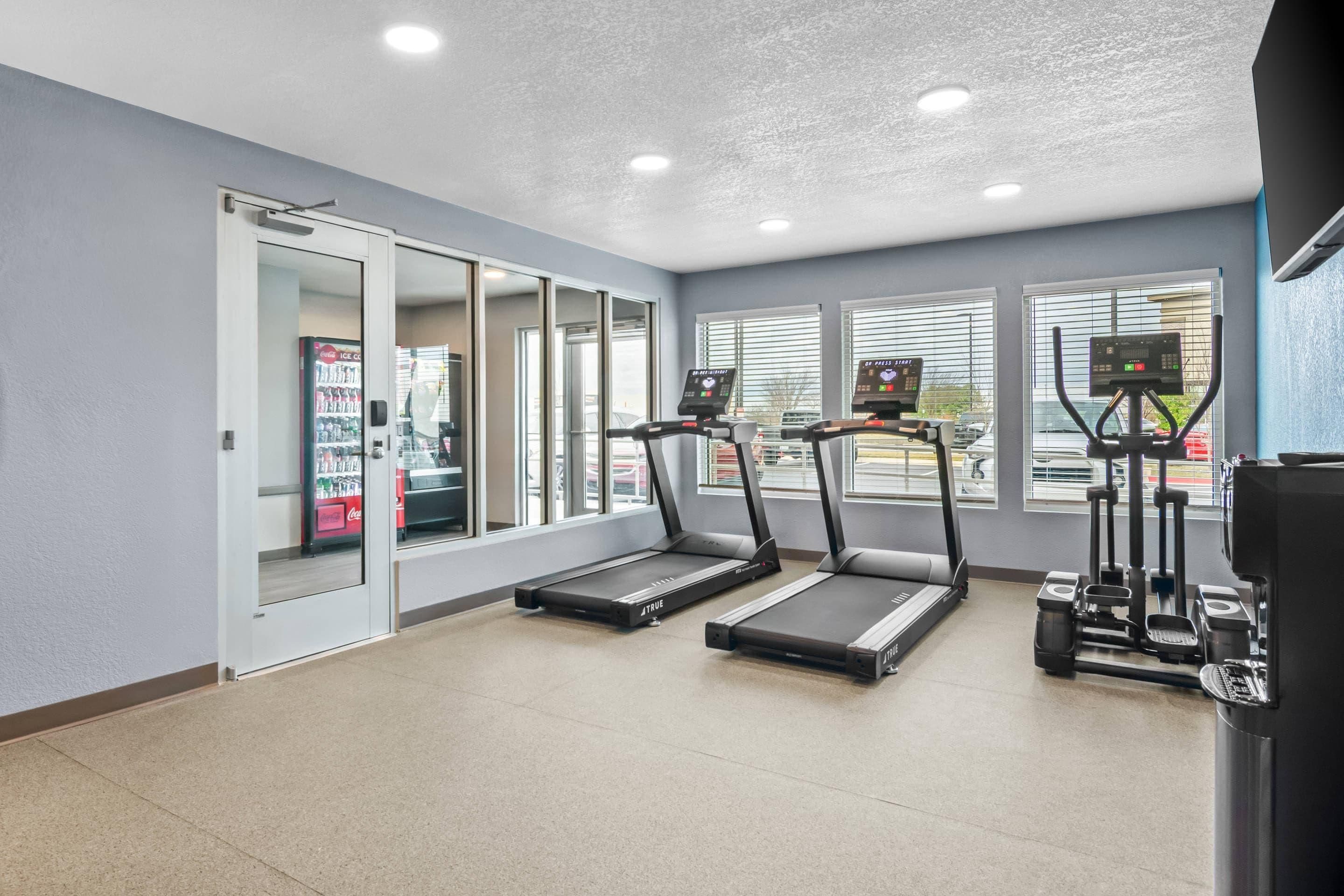 A gym with treadmills, a stationary bike, and a rowing machine.