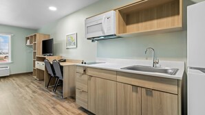 Una cucina moderna con mobili in legno, forno a microonde integrato, lavello e televisore.