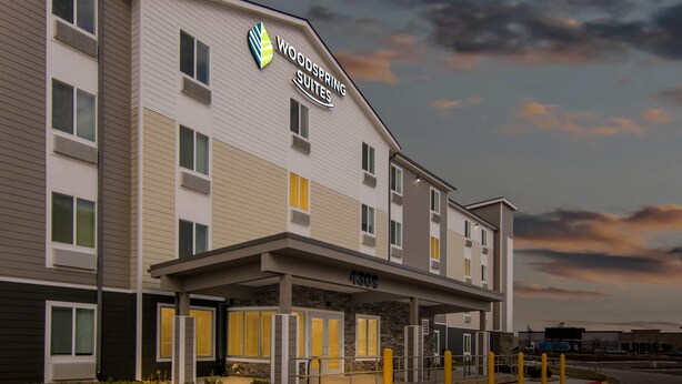 Un hotel de diseño moderno, una entrada cubierta y un cartel que indica que es un Woodspring Suites.