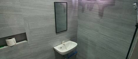A bathroom with a toilet, sink, and shower.