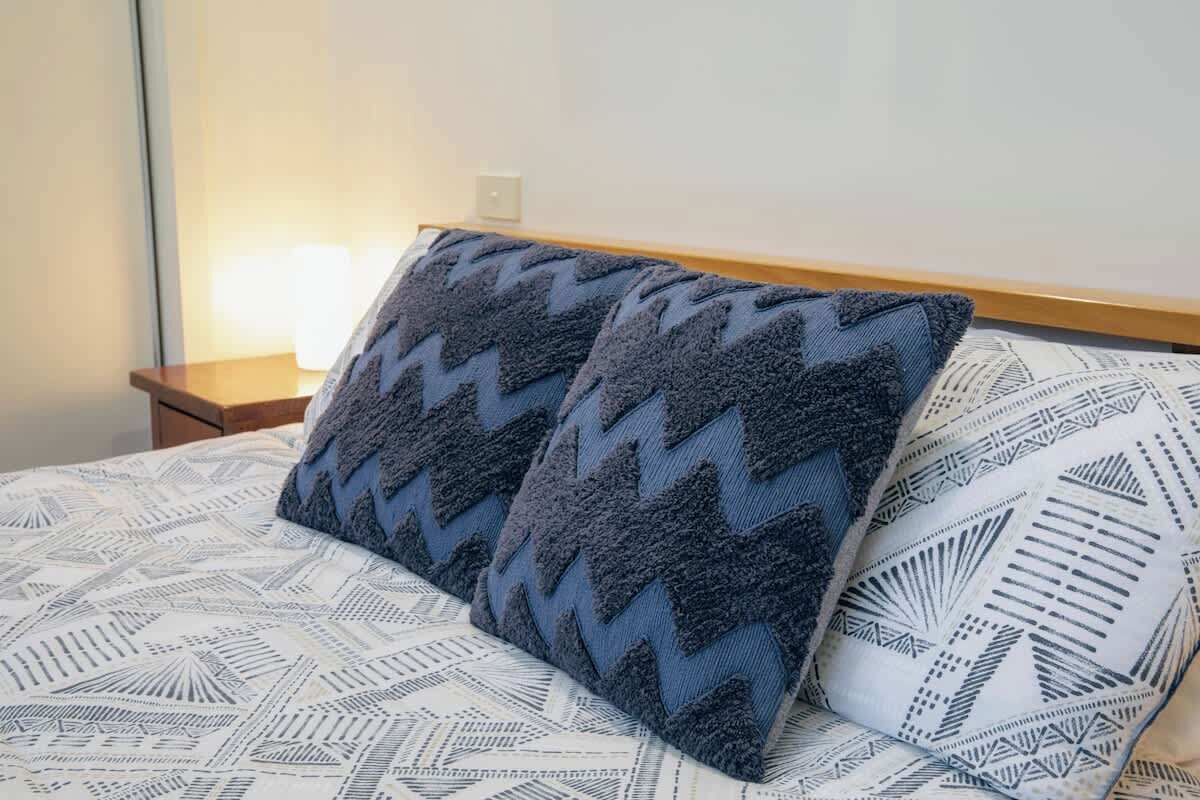 A bed with patterned bedding and two pillows.