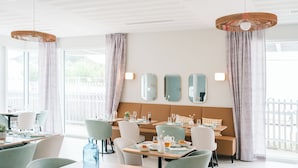 Un espace repas lumineux, avec des tables, des chaises et un canapé.