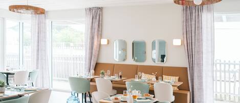 A bright dining area with tables, chairs, and a sofa.