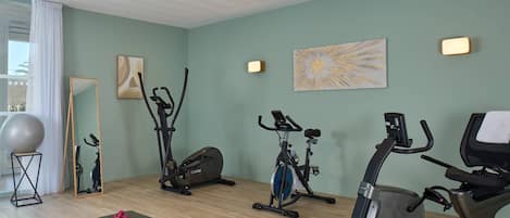 A home gym with exercise equipment, a yoga mat, and a mirror.