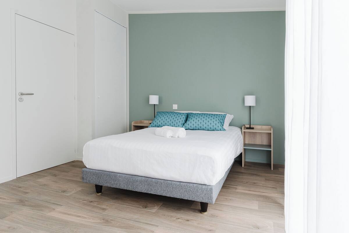 Ein Schlafzimmer mit einem Bett, zwei Nachttischen und einer Tür.