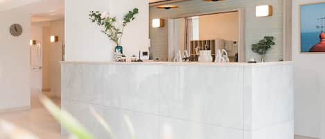 A reception area with a marble counter, potted plants, and pendant lighting.
