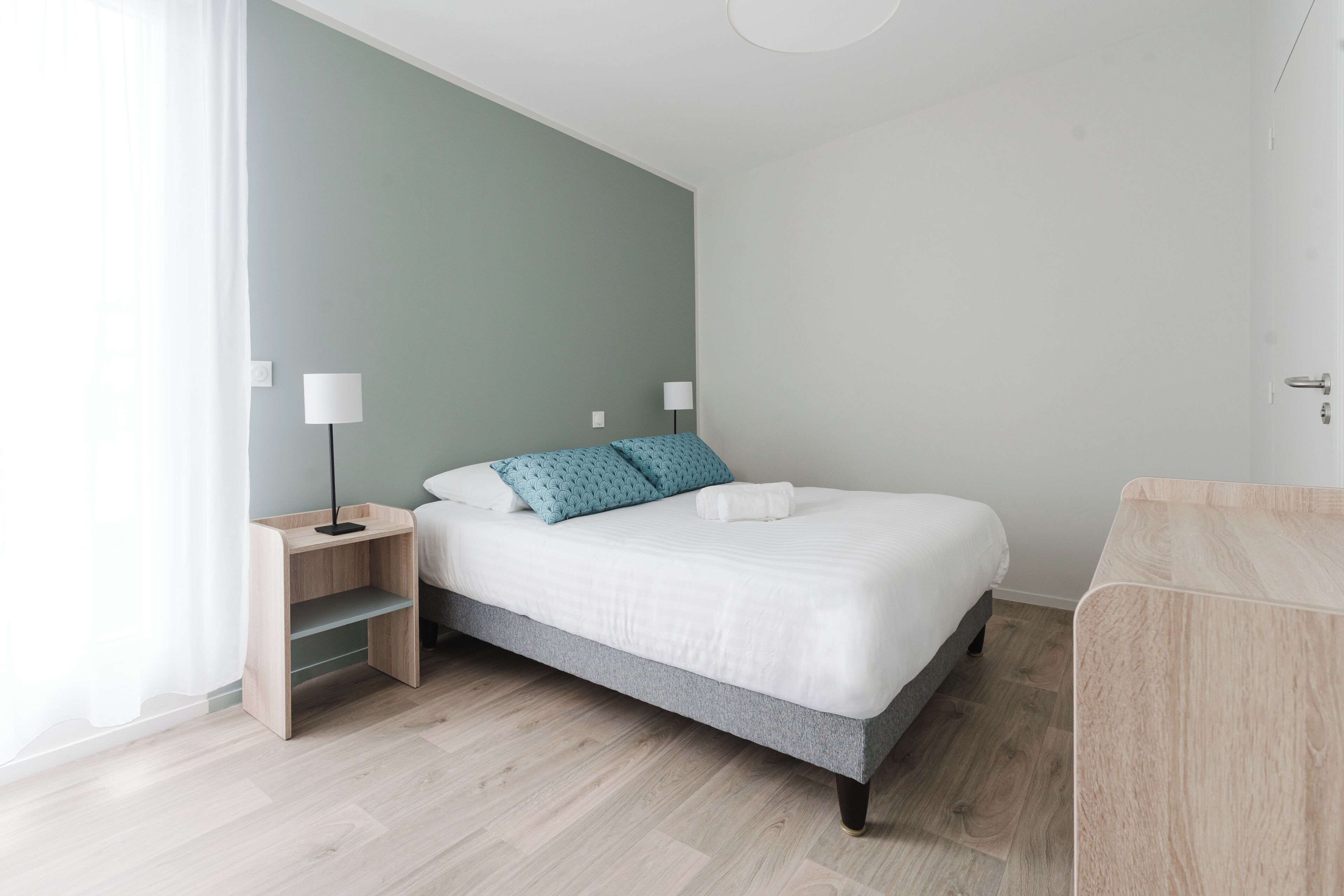 A modern bedroom with a bed, bedside tables, and a nightstand.