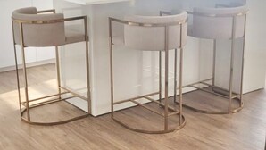 A modern kitchen with white cabinetry, a central island, and three bar stools with gold frames. - Apartment Apulia - sea view 6 people (Apúlia esposende)