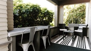 An outdoor patio with a metal table and two chairs, a small table with a chair, and a black and white striped rug. - Outsite San Diego - Golden Hill - Work, Connect, Explore (San Diego)