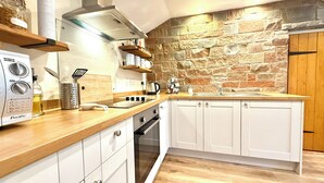 Une cuisine moderne avec des armoires blanches, un pare-feu en pierre et un plan de travail en bois.