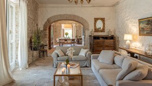 A spacious living room with a stone wall, a wooden dining table, and a sofa set. - Villa la Pizzichina 10 Emma Villas (Todi)