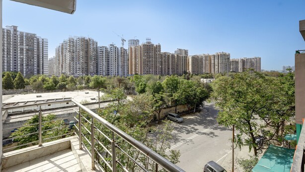 A high-rise building with multiple floors, a parking area, and trees in the foreground. - Hotel Spectrum Inn - By ASPL (Noida)