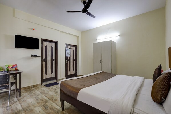 A hotel room with a bed, a desk, a chair, a wardrobe, and a television. - Hotel Spectrum Inn - By ASPL (Noida)