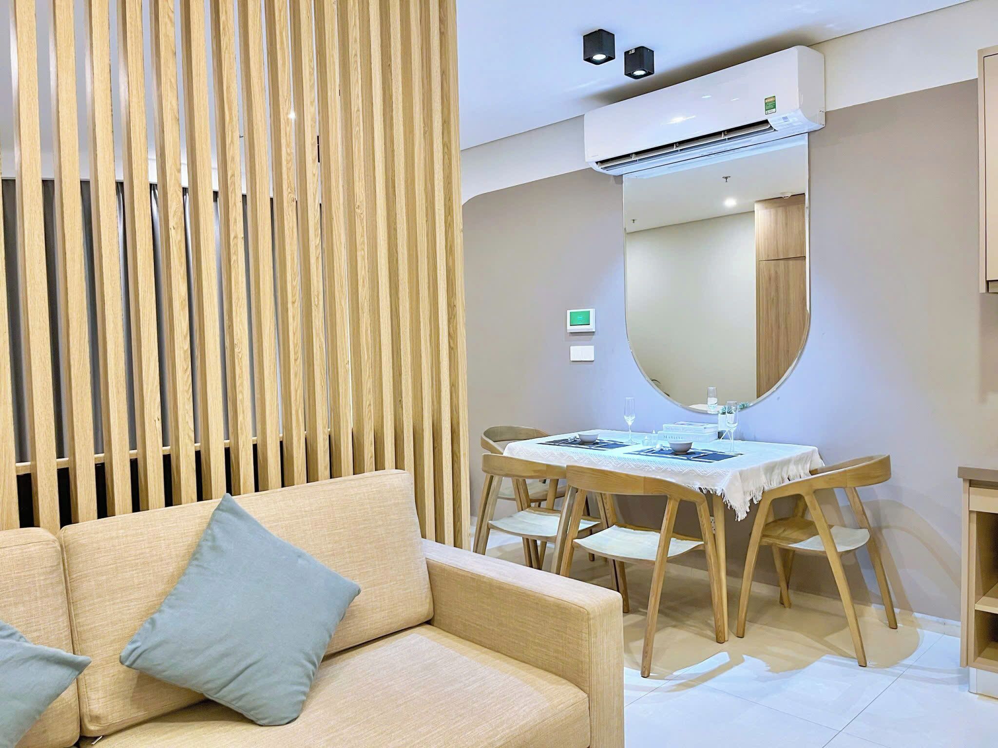 A modern room with a sofa, dining table, chairs, and an air conditioning unit.