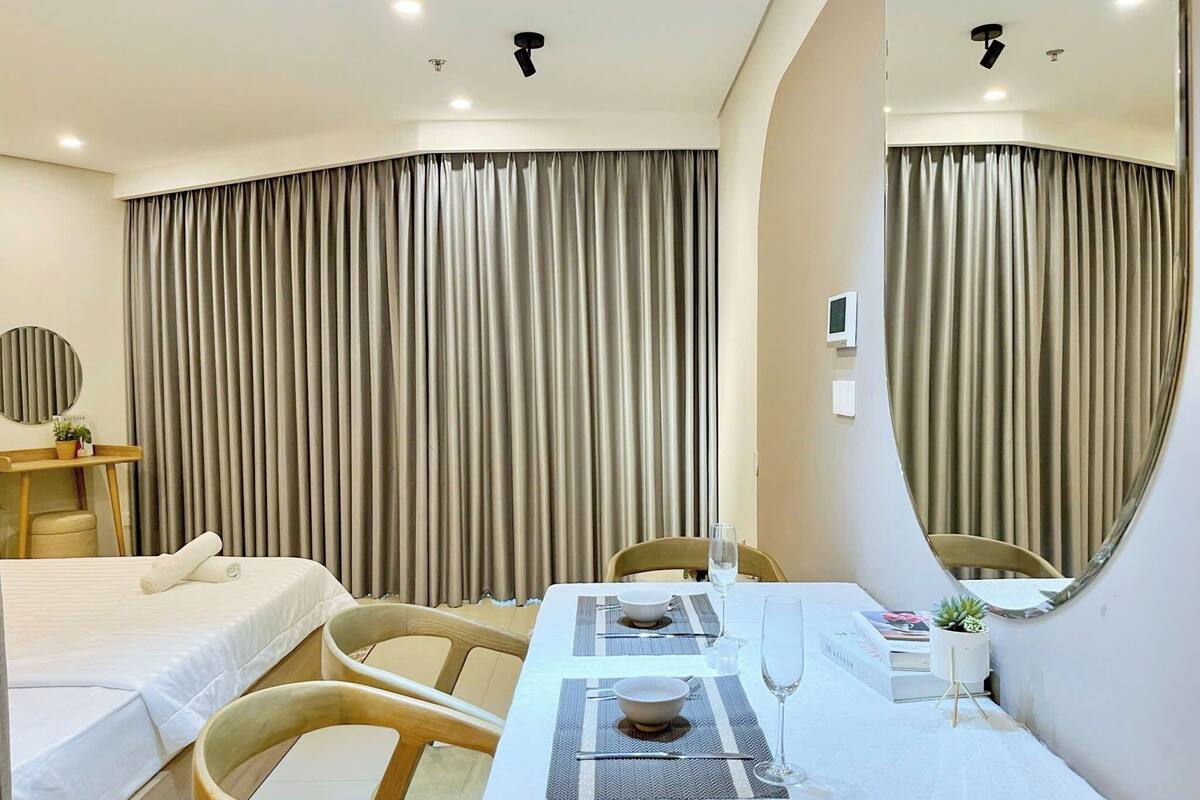 Une chambre d’hôtel avec un lit, une table à manger dressée pour deux personnes et un grand miroir.