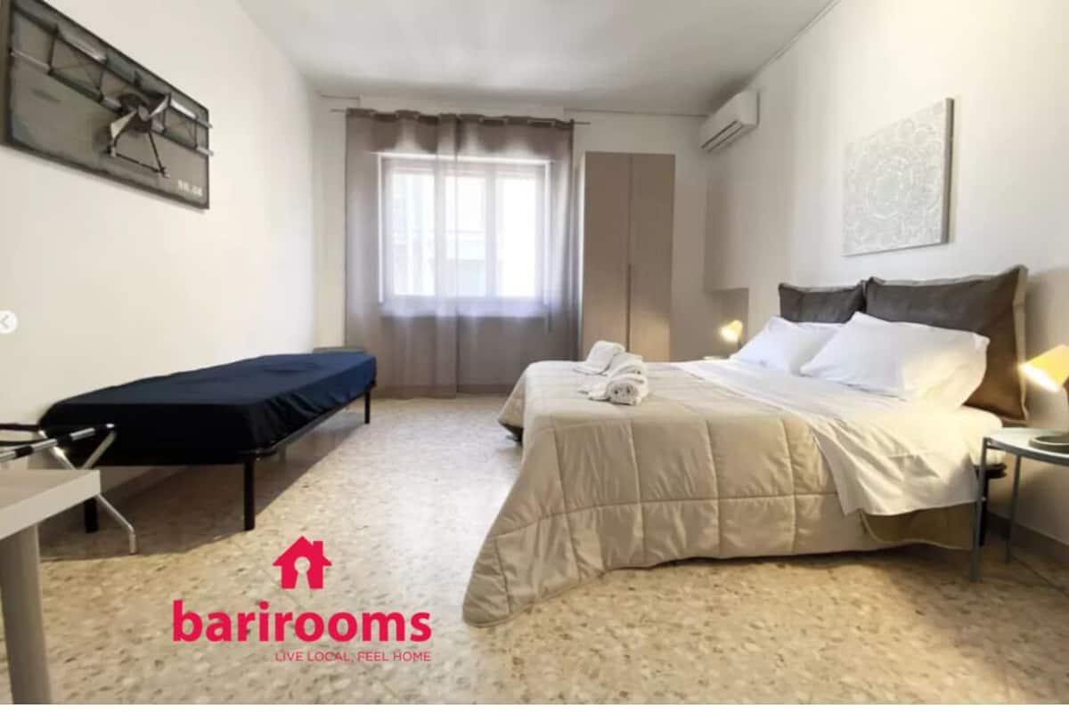 A hotel room with a bed, bedside table, and a window with curtains.