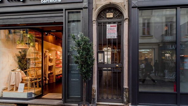 Une vitrine donnant sur la rue, avec des meubles exposés derrière une vitre et une pancarte indiquant une vente.