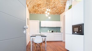 Une cuisine moderne avec des meubles blancs, une table à manger en bois et un luminaire suspendu.