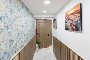 A hallway with a floral wallpaper, a cityscape painting, and a wooden slatted wall. - Bety Dreams Apartments (Madrid)
