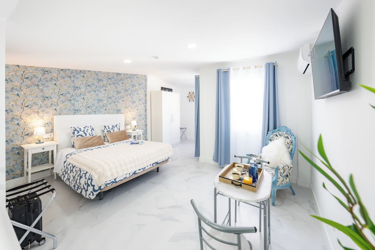 Een moderne hotelkamer met een groot bed, een bureau met een tray toiletartikelen, een stoel en een aan de muur bevestigde televisie.
