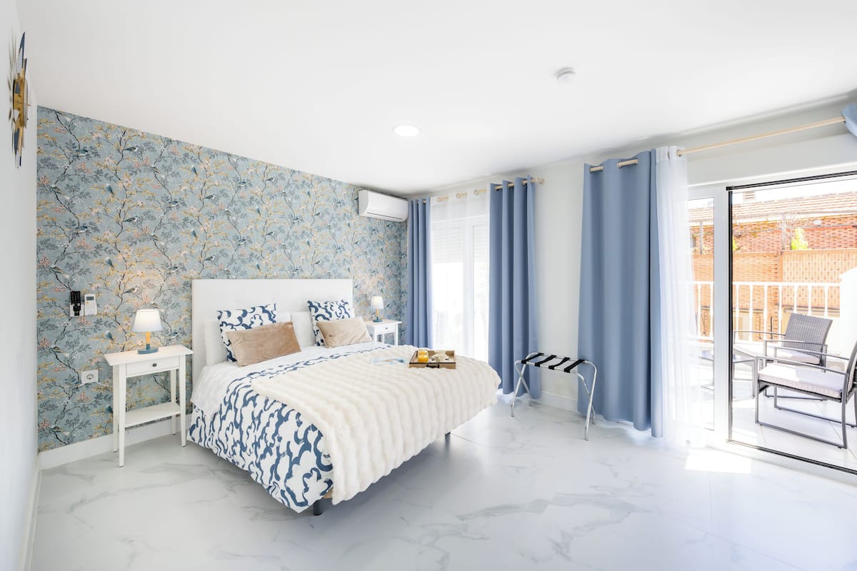 Een slaapkamer met een bed, nachtkastje en uitzicht.
