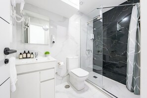 A modern bathroom with a white vanity, a toilet, a glass shower enclosure, and a marble backsplash. - Bety Dreams Apartments (Madrid)