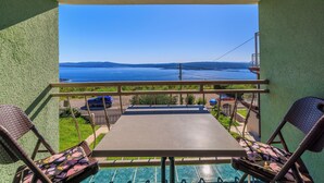 A balcony with a view of the sea, a pool, and a table with chairs. - Apartman Mistral 4 (Crikvenica)
