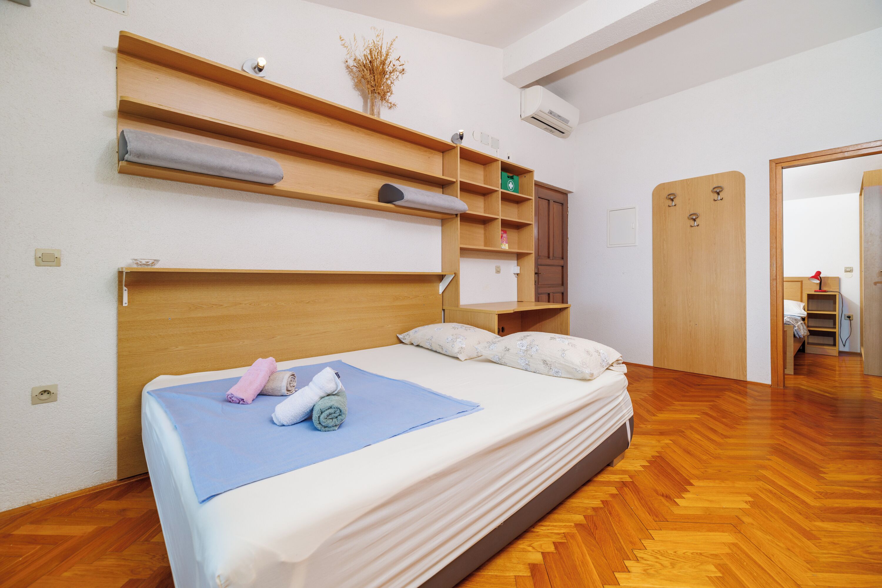 Une chambre bien rangée, avec un lit, des étagères en bois et une armoire.