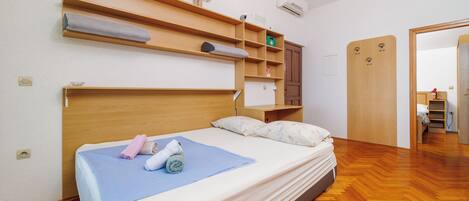 A neatly arranged bedroom with a bed, wooden shelves, and a wardrobe.