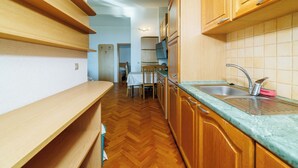 A kitchen with wooden cabinets, a sink, and a herringbone floor. - Apartman Mistral 4 (Crikvenica)