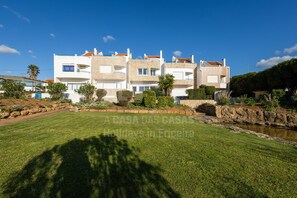 Stunning multi-story residence with a serene atmosphere, featuring a well-manicured lawn and a small water feature.