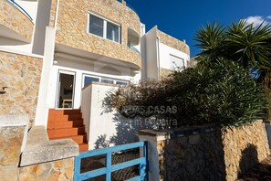 Stunning stone building with a blue door, surrounded by lush greenery and a vibrant entrance.