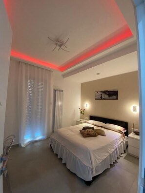 A spacious bedroom with a large bed, a ceiling fan, and a modern light fixture. - Mamuccia Rooms (Naples)